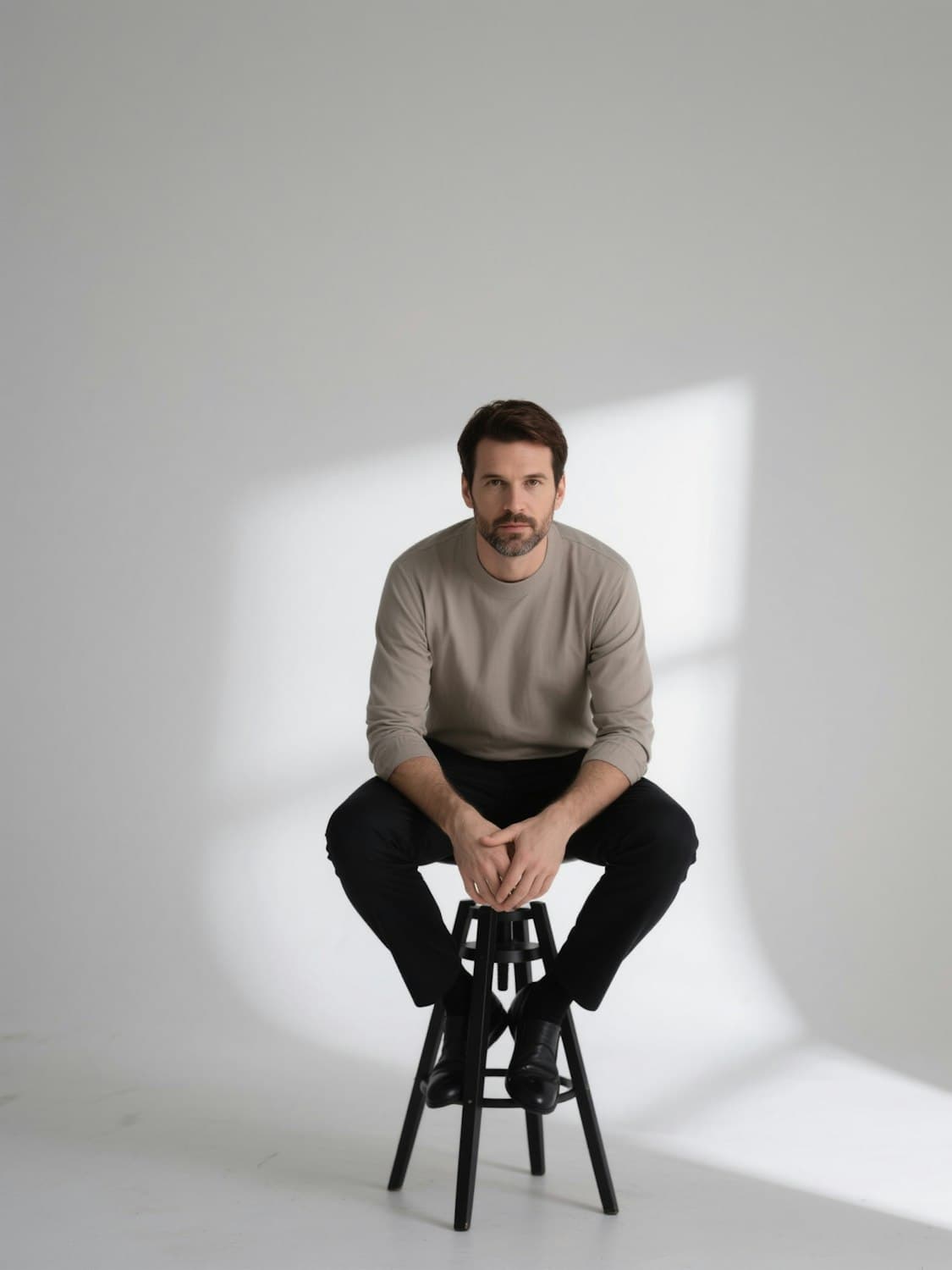 Studio portrait of a seated subject against a plain backdrop